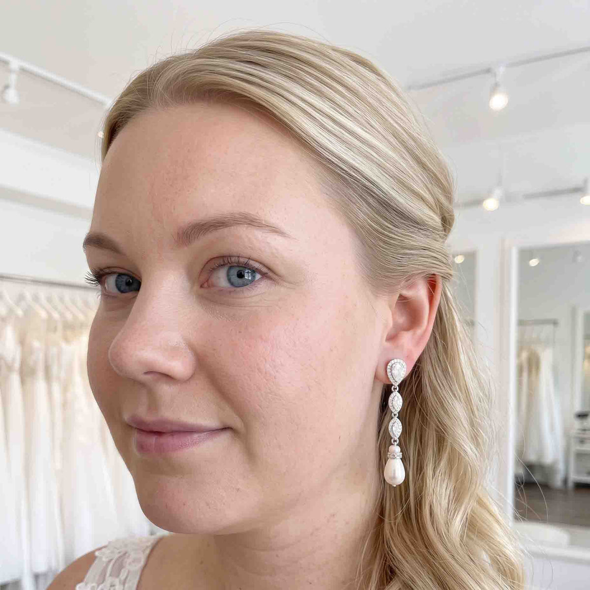 Close-up of an Abby silver crystal and pearl earring worn with a half-up bridal hairstyle.