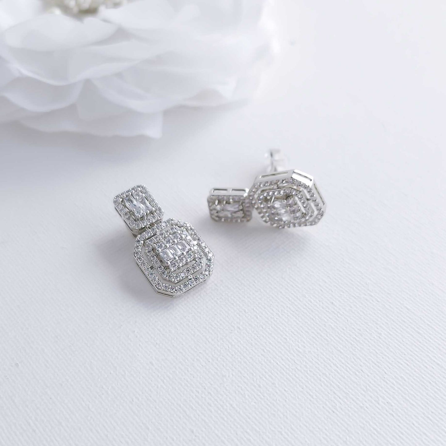 Silver earrings with gemstones on a white fabric background
