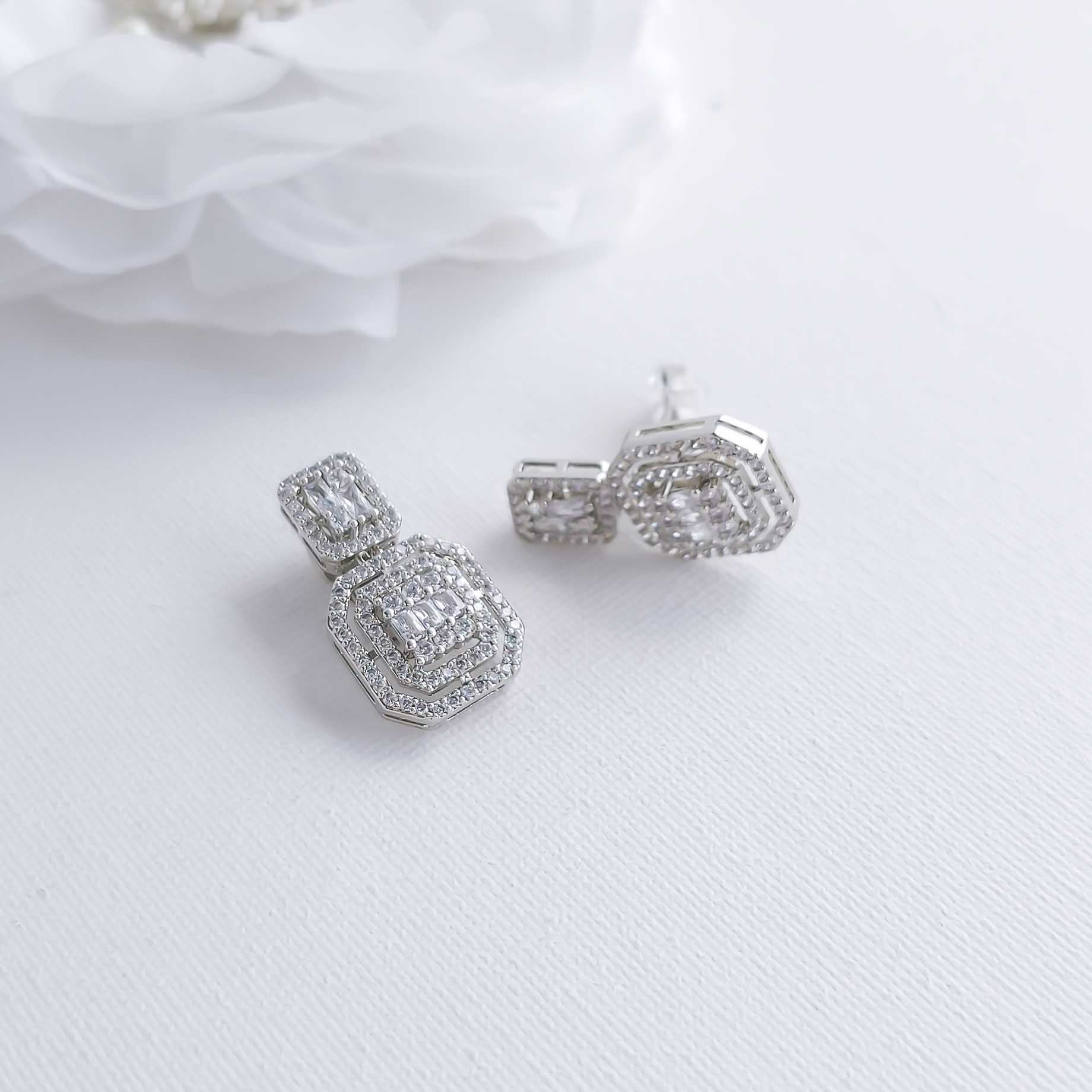 Silver earrings with gemstones on a white fabric background