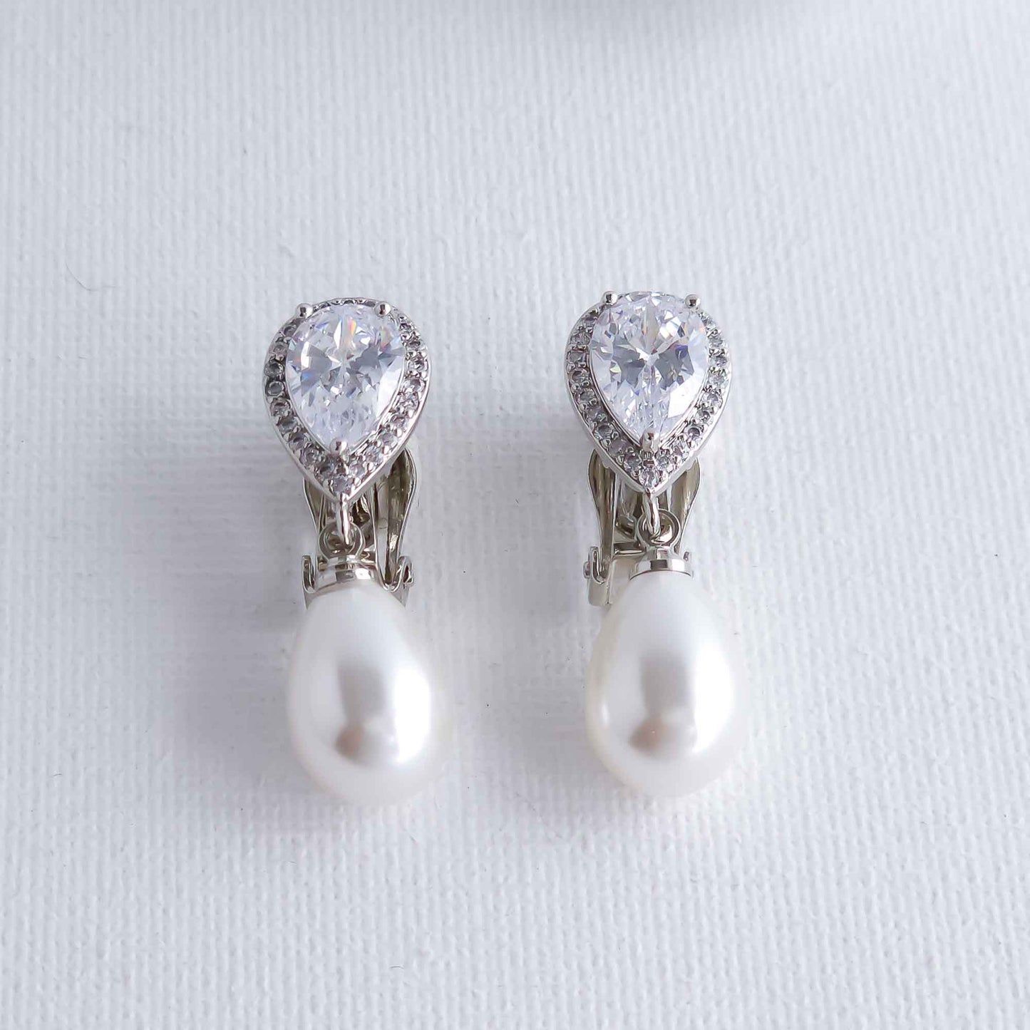 Pearl and crystal teardrop clip earrings on a light gray background