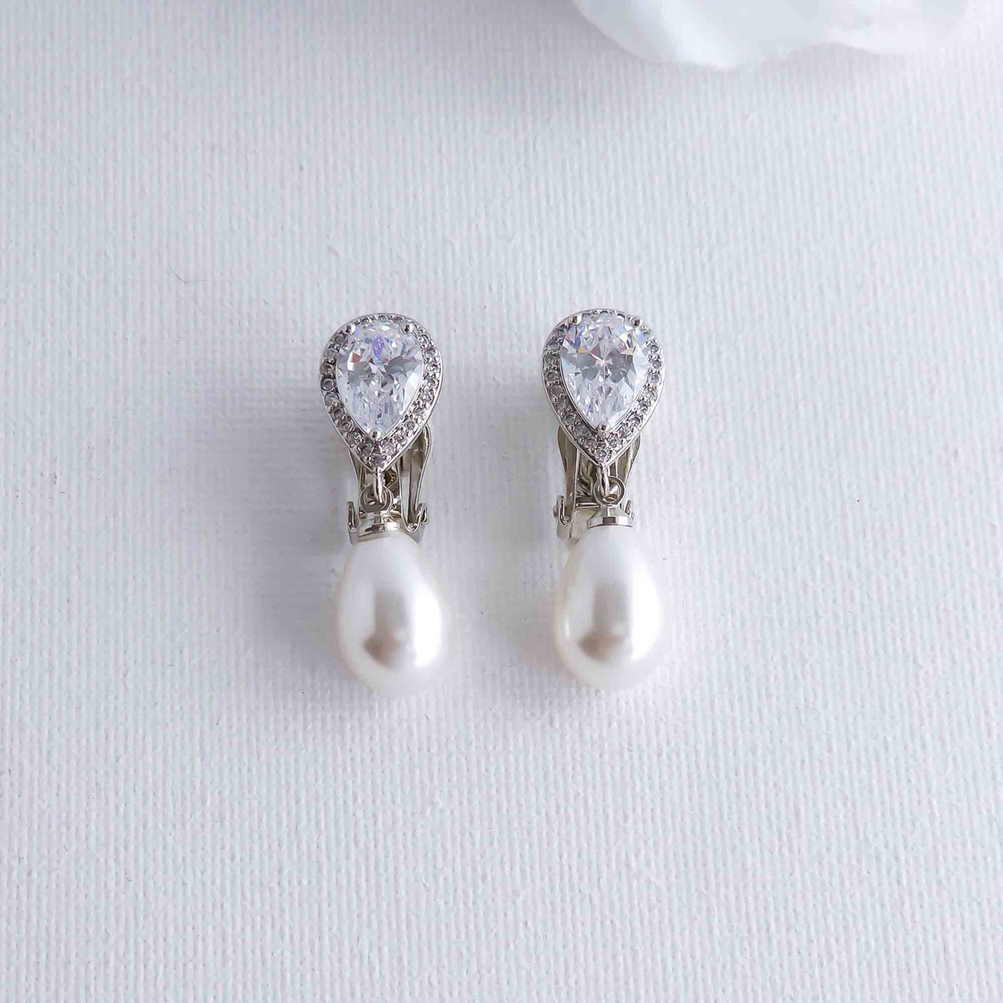 clip on Pearl and crystal teardrop earrings on a light gray background