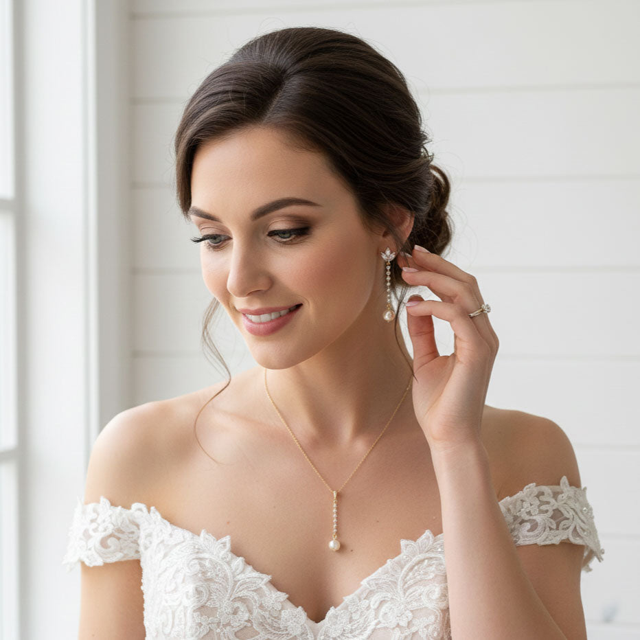 Woman wearing a Pearl Drop Earrings in Rose Gold with white lace dress with jewelry, smiling.
