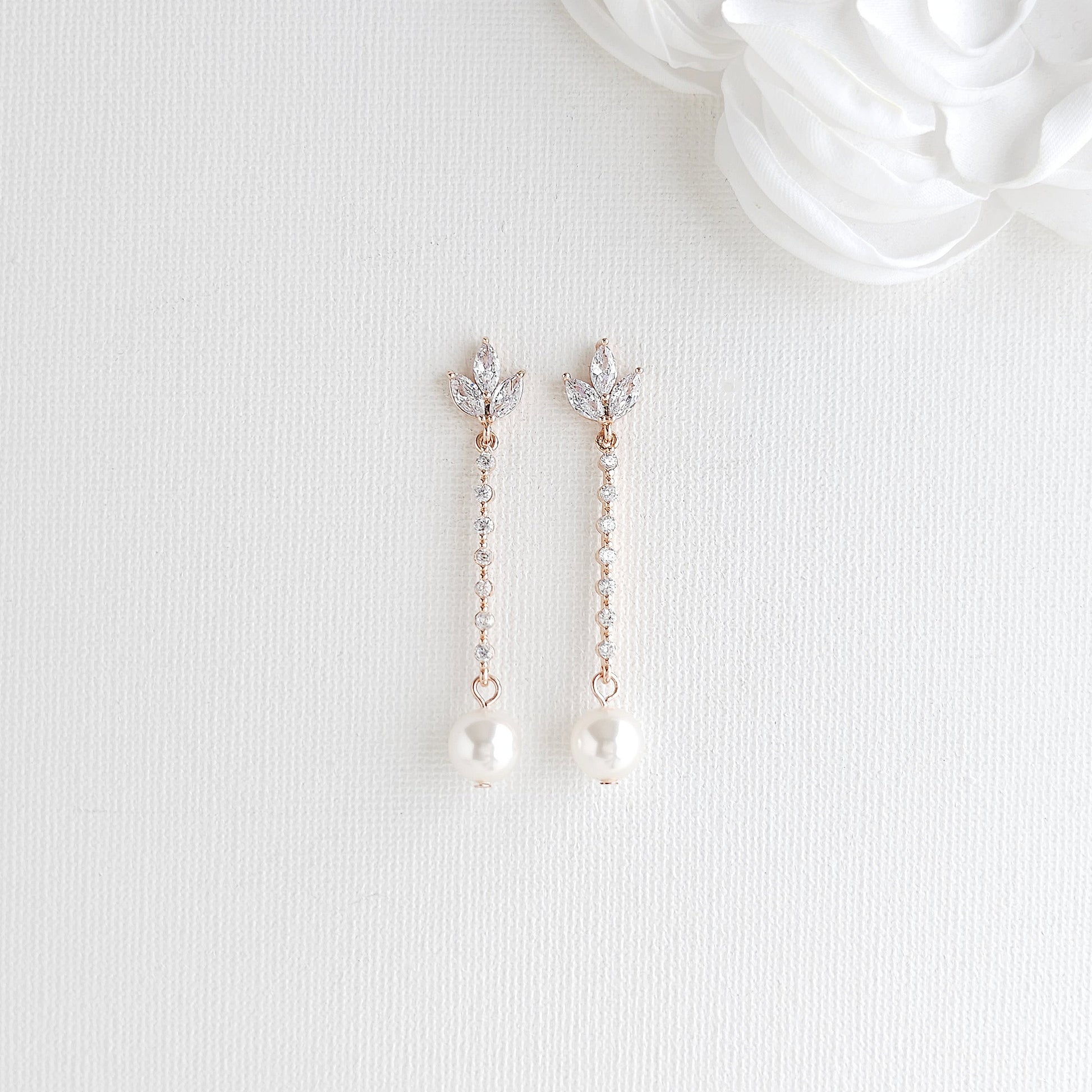 Pair of delicate Pearl Drop Earrings in Rose Gold with pearls and crystals on a white background