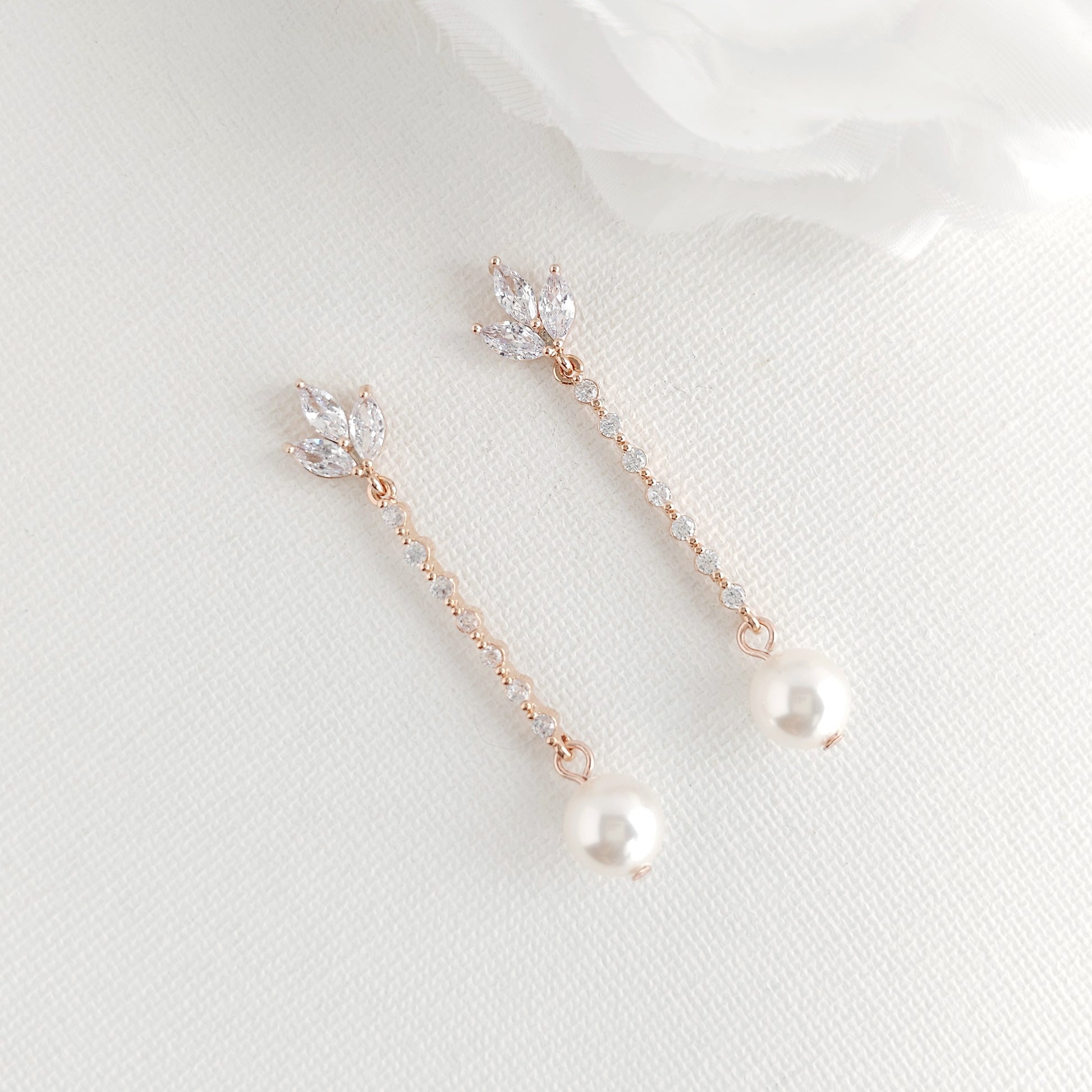 Rose gold earrings with pearls on a light gray background