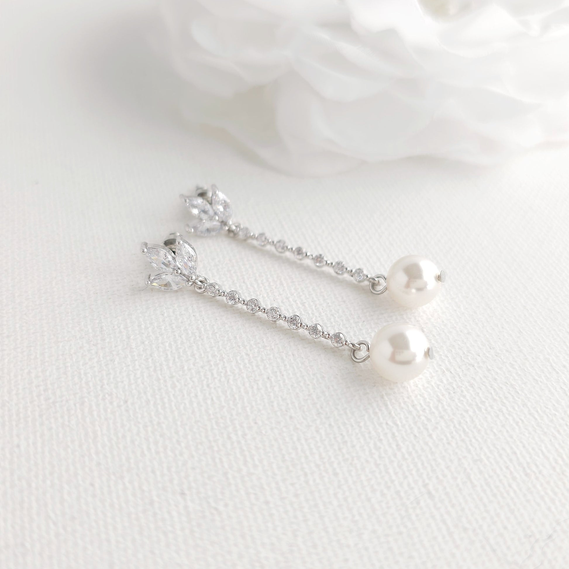 Pair of pearl earrings on a white fabric background