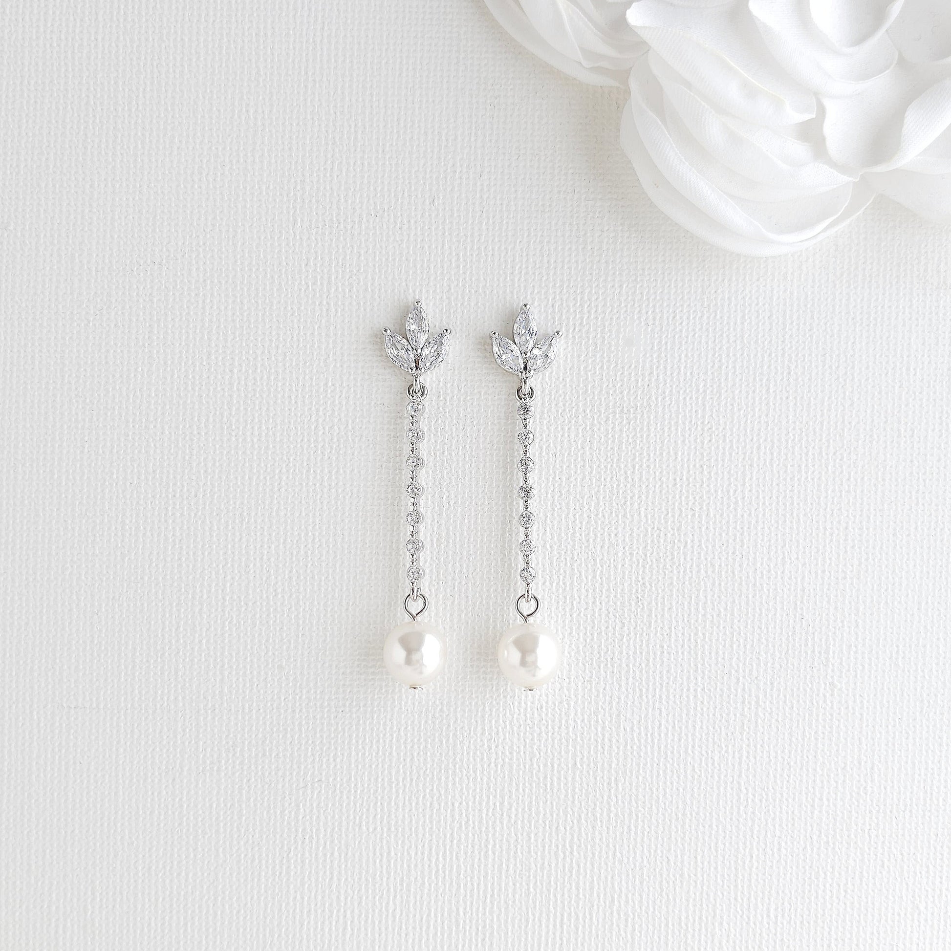 Pair of silver earrings with pearl drops on a white background
